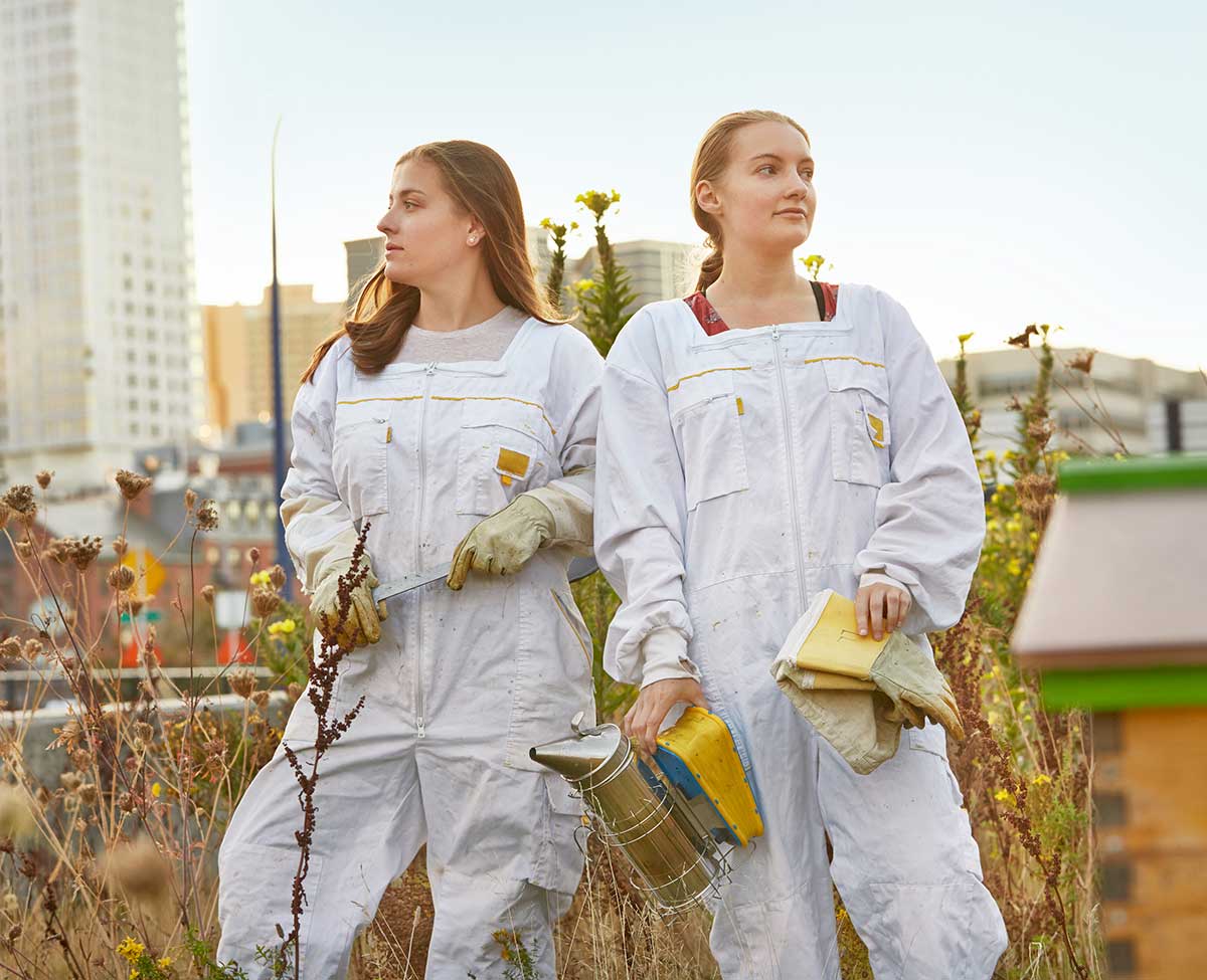 Two female beekeepers urban beekeeping standing in city green space