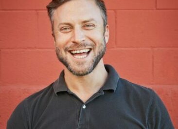 Headshot of Noah Wilson-Rich on a red background