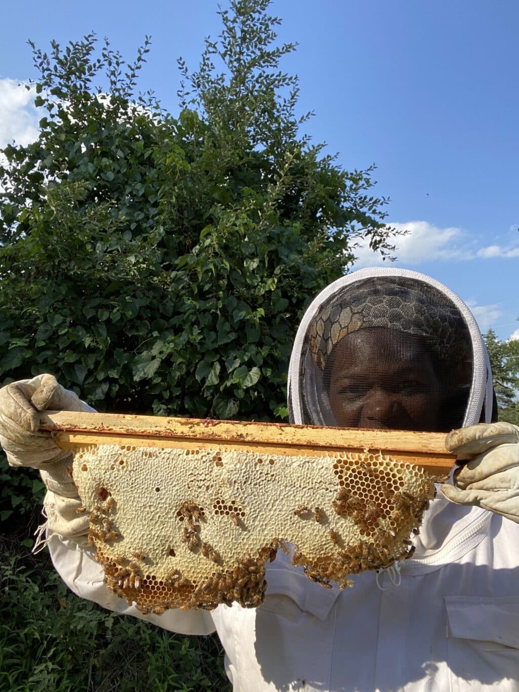 Tameeka holding a frame of bees and honey.