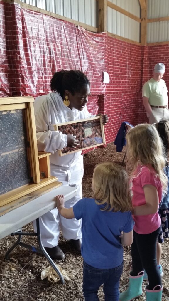 Tameeka teaching children about bees next to an observation hive.