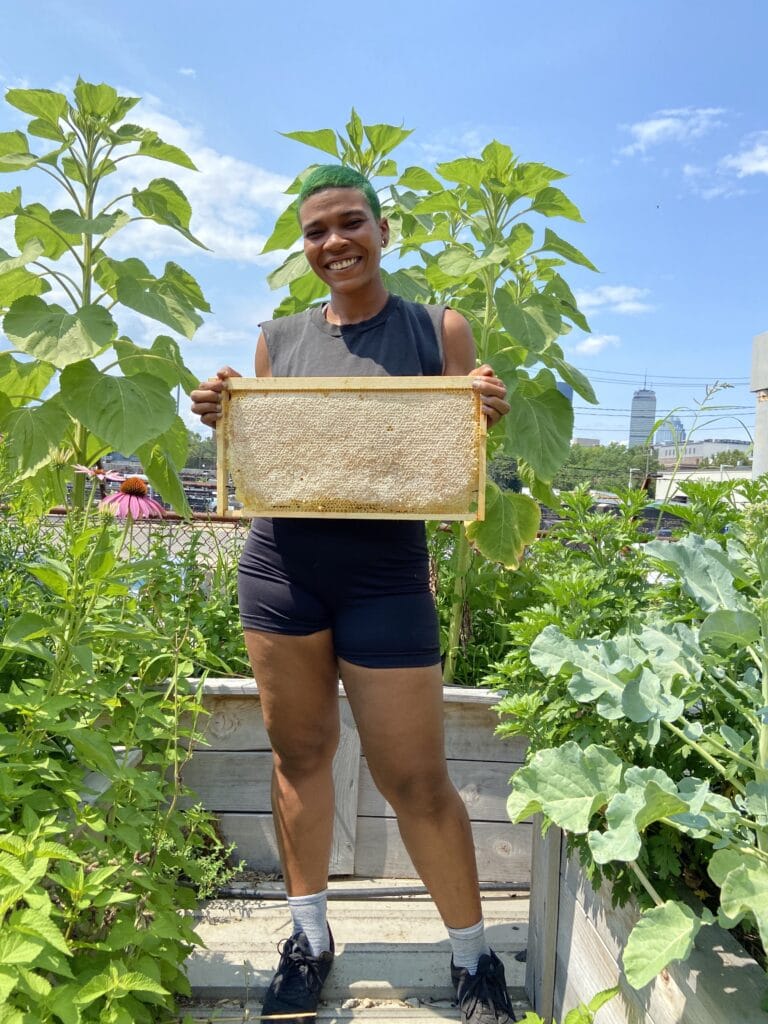Che holding a honeybee hive frame