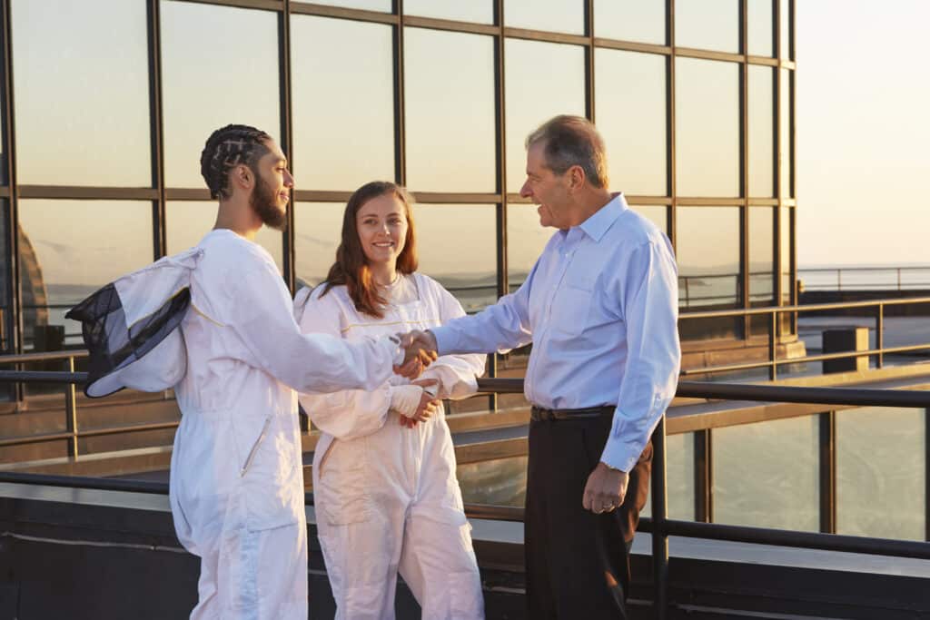 Beekeepers on roof of 53 State St shaking hands with client