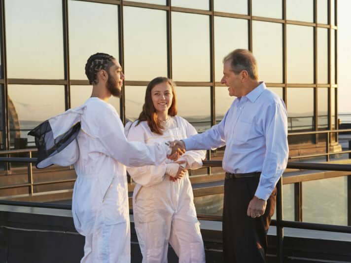 Beekeepers on roof of 53 State St shaking hands with client