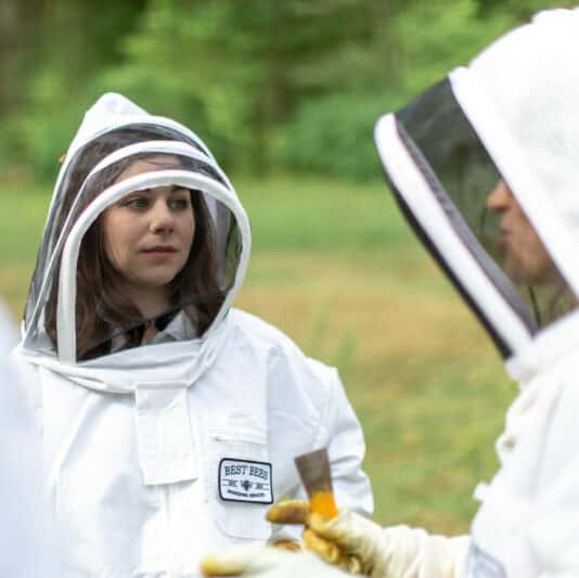 Student engages with pollinator educational demonstration, wearing a bee suit