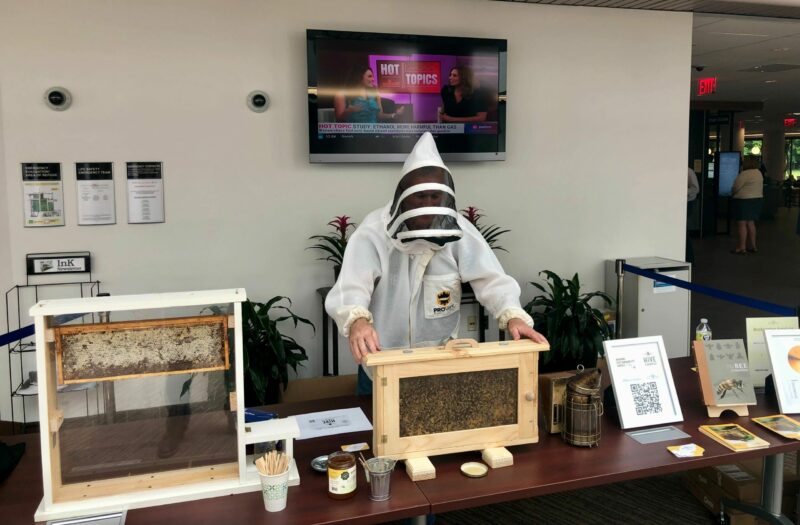 A beekeeper standing behind a demonstration table at an educational event