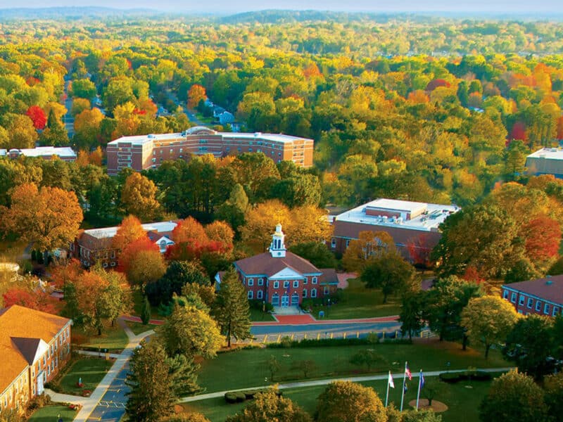 aerial drone shot of university surrounded by fall foliage