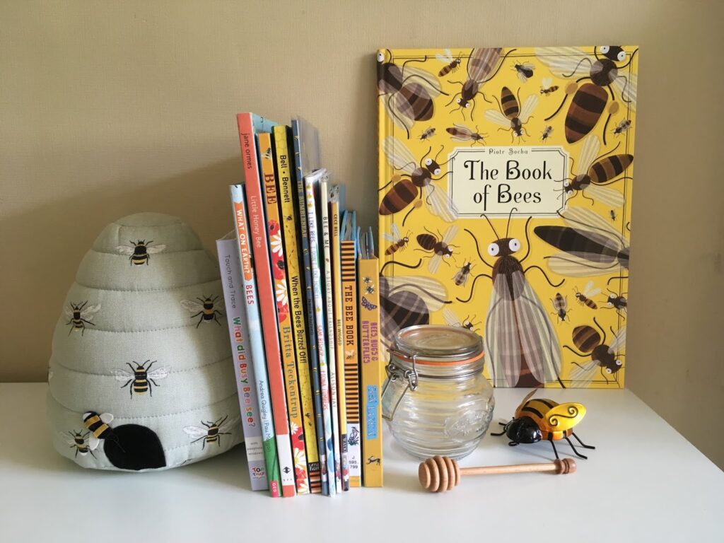 Books about bees arranged on a shelf with a mini honey jar