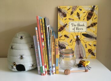 Books about bees arranged on a shelf with a mini honey jar