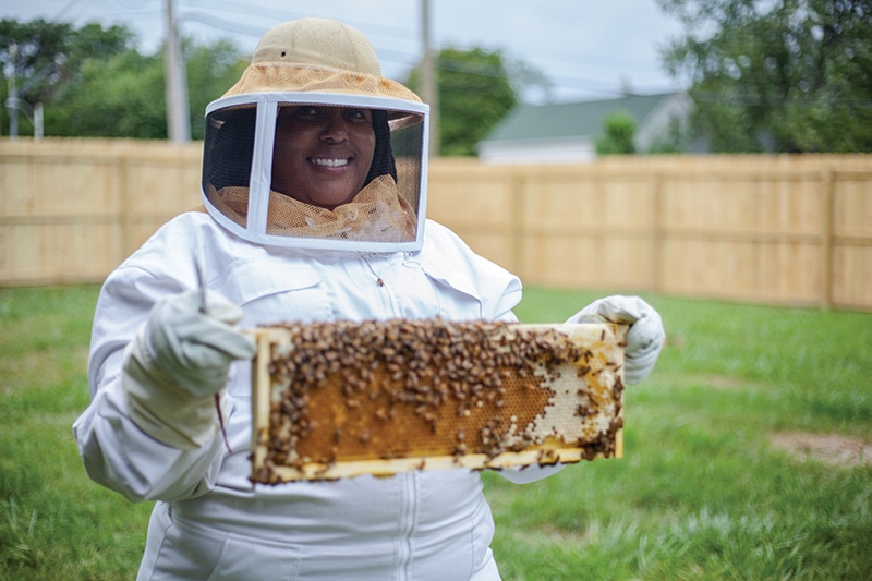 BIPOC beekeeper holding a frame of bees