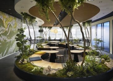 This meeting room's biophilic design emphasizes lush greenery, natural materials like wood, and organic shapes and curves.