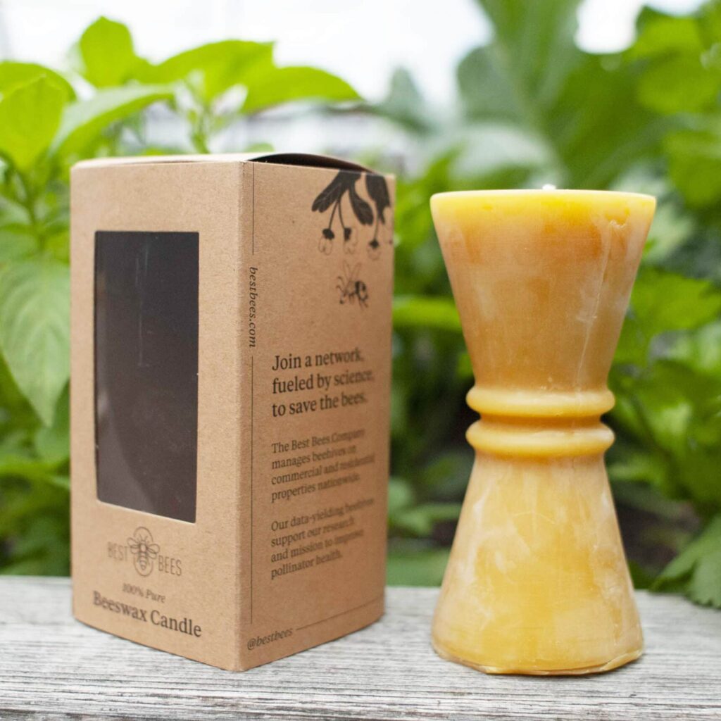 Beeswax candle next to box, with leaves in the background