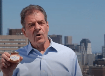 Al standing on a rooftop holding a jar of honey