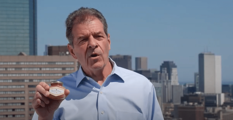 Al standing on a rooftop holding a jar of honey